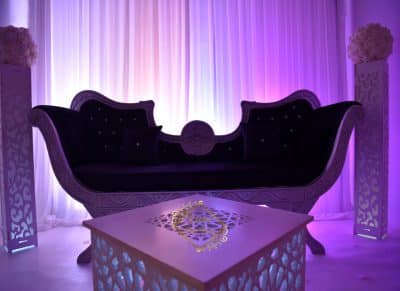 Canapé-trône noir et argent pour événement oriental de luxe. Décoration avec table lumineuse sculptée et éclairage pourpre intense.