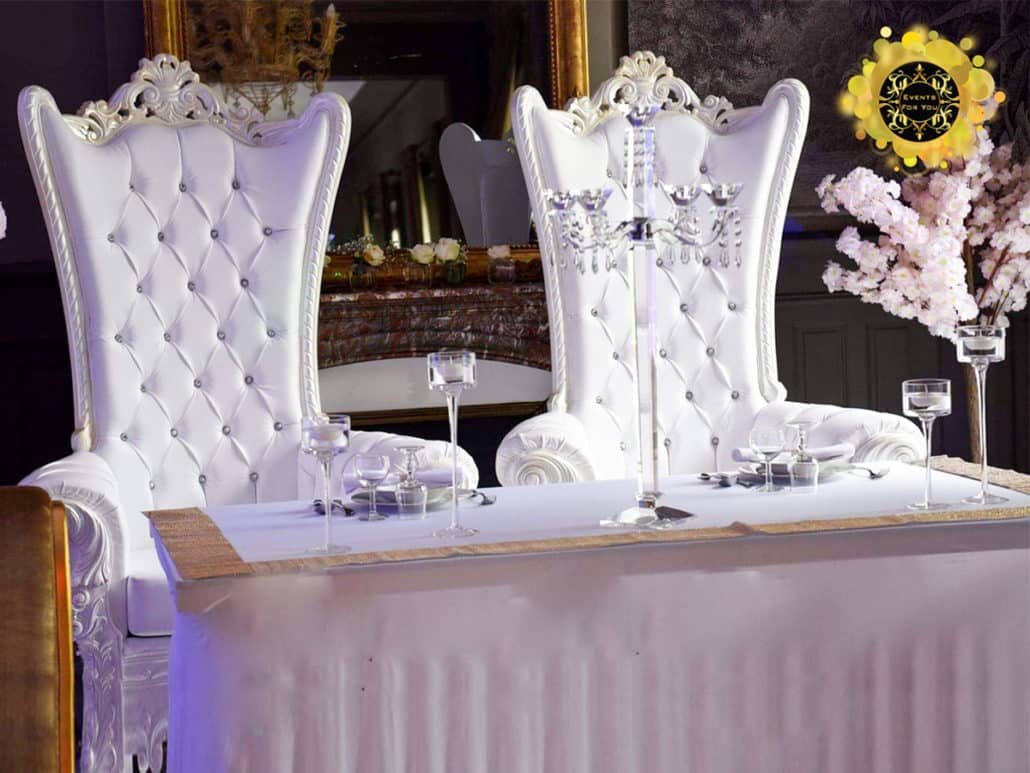Table d'honneur luxueuse avec deux chaises trônes capitonnées blanches à dossiers hauts, décorées de cristal. Logo EVENTS FOR YOU.