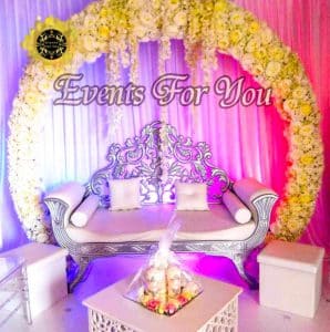 Luxueuse scène événementielle "Events For You" : divan argenté orné, arche florale blanche et rose, éclairage romantique violet.