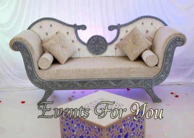 Luxueuse banquette de réception beige et argent vieilli, avec coussins et table lumineuse. Décor d'événement. Texte: Events For You.