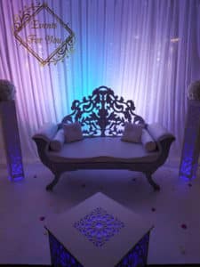 Luxueux sofa nuptial blanc orné sur podium. Décor événementiel élégant avec voilage, éclairage LED bleu et violet. Logo "Events For You".