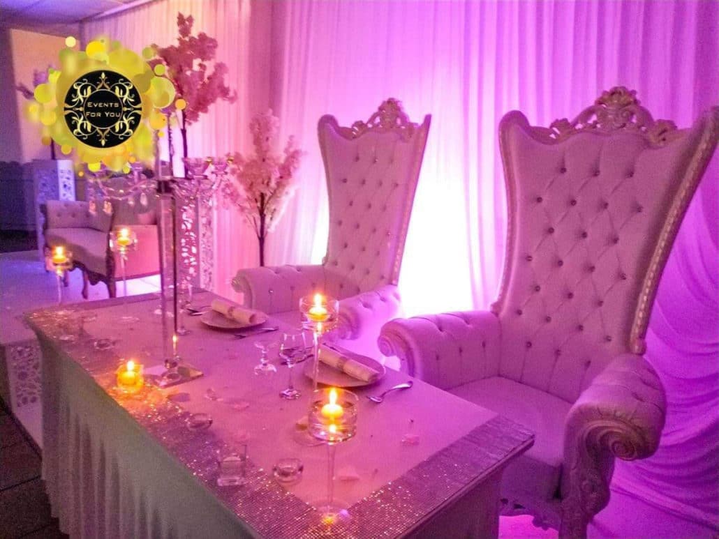 Table d'honneur de luxe avec deux chaises trône capitonnées, décor rose scintillant, éclairage magenta et bougies (Events For You).