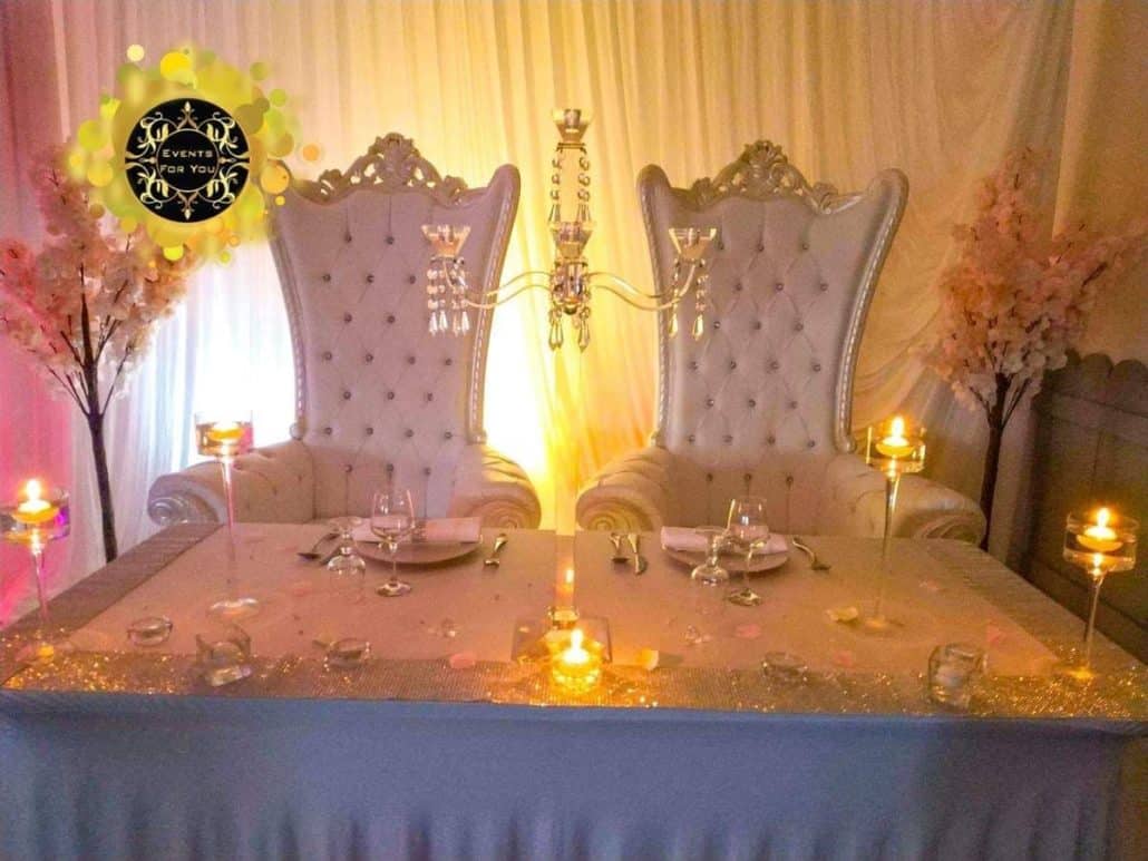 Luxueuse table des mariés avec deux fauteuils trônes blancs, chandelier, arbres en fleurs et bougies. Logo "EVENTS FOR YOU".