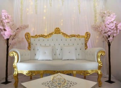 Trône de mariage blanc et or sculpté, avec capitonnage. Décor de scène avec voilages lumineux et cerisiers en fleurs roses.